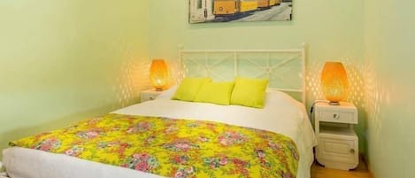 A bed with a floral bedspread, two pillows, and two bedside lamps.
