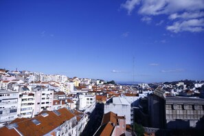 A cityscape with densely packed buildings, a prominent church with a large bell tower, and a clear blue sky. - Casa Belmonte (Lisbon)