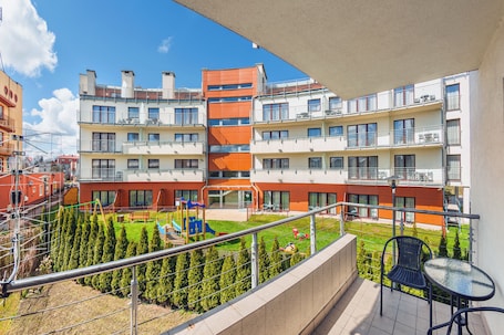 A balcony with a view of a playground and a building with multiple balconies.