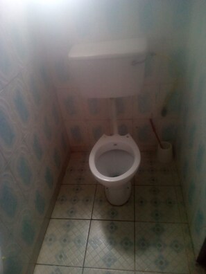 Een kleine badkamer met een toilet, een bidet en een toiletrolhouder.
