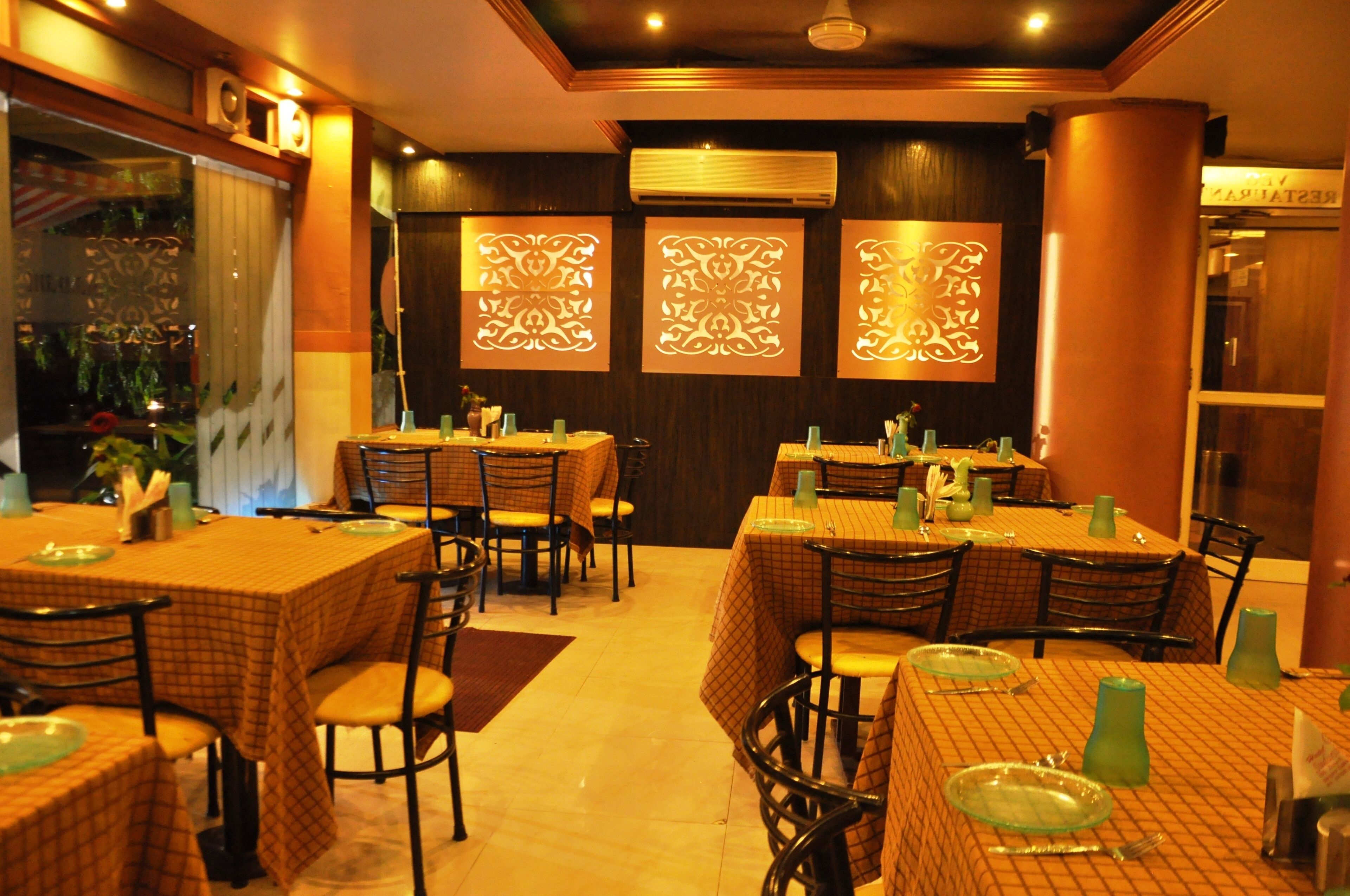 Un restaurant doté de nombreuses tables, de chaises et de panneaux décoratifs sur les murs.