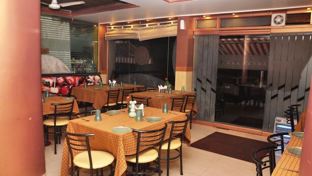 Un restaurant avec plusieurs tables et chaises, un ventilateur de plafond et une grande fenêtre donnant sur la rue.