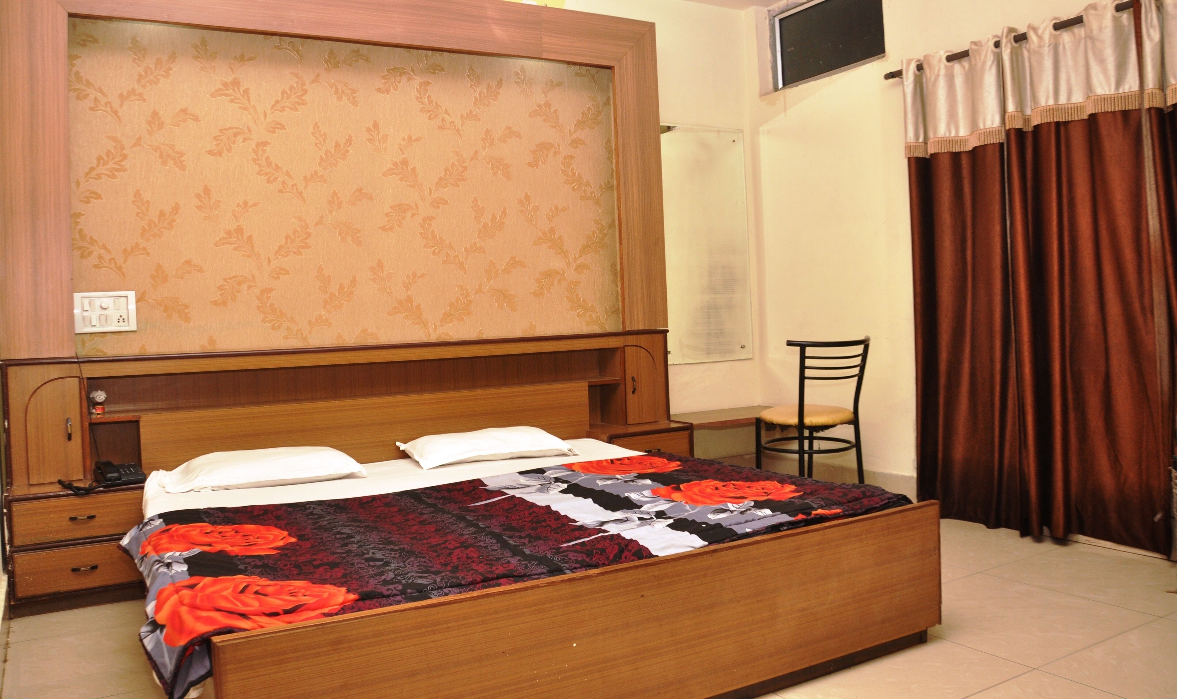 A bedroom with a wooden bed, a nightstand, a chair, and a window with curtains.