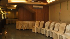 Une salle de conférence dotée d’un ventilateur de plafond, de rangées de chaises recouvertes, d’une longue table et d’un appareil de climatisation.