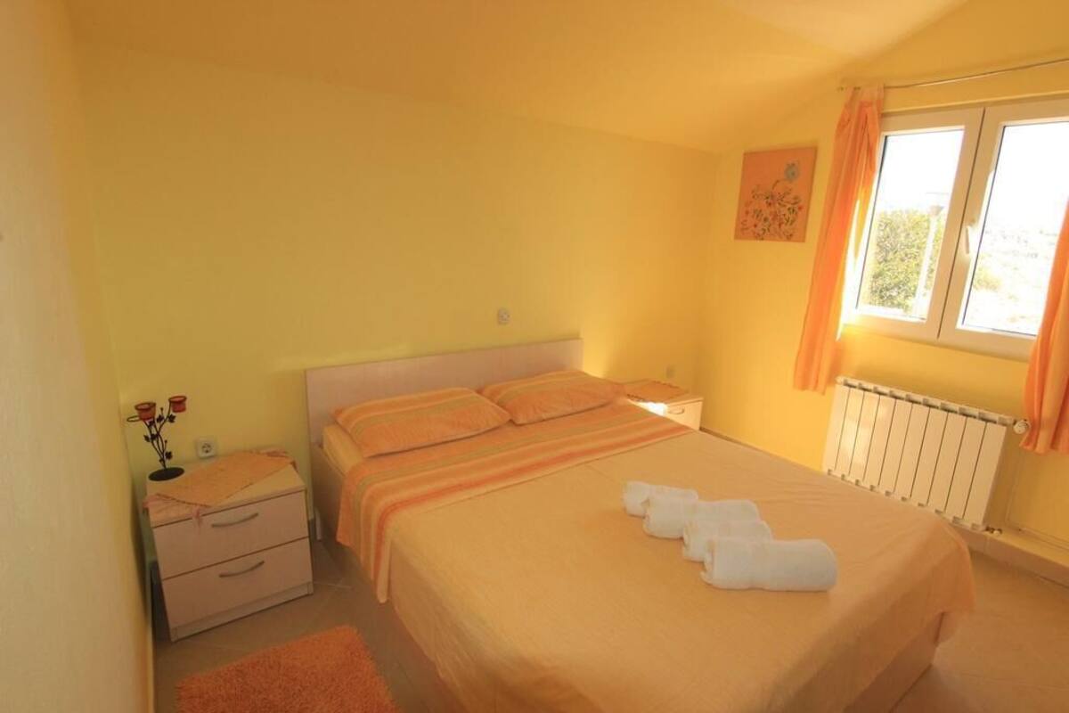 Une chambre à coucher avec un lit, des tables de chevet, un radiateur et une fenêtre avec des rideaux.