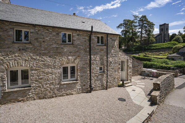 A stone building with a gravel driveway and a small patio area.