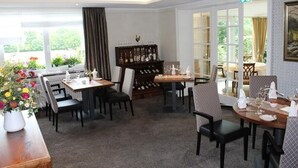 A hotel dining area with tables set for dining, a wine rack, and a view of the outdoors. - Landgasthof Gut Marienbildchen (Roetgen)
