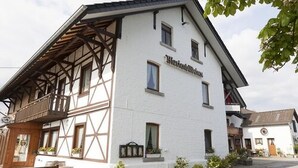 A traditional half-timbered building with a balcony and potted plants. - Landgasthof Gut Marienbildchen (Roetgen)