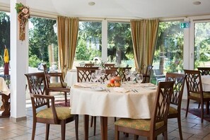 Un comedor con una mesa redonda dispuesta para seis personas, rodeada de sillas de madera con asientos acolchados.