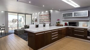 Una cocina moderna con una isla grande, armarios oscuros y vistas al exterior.