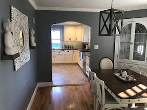 Une cuisine moderne avec des meubles blancs, une table à manger en bois et un miroir décoratif.