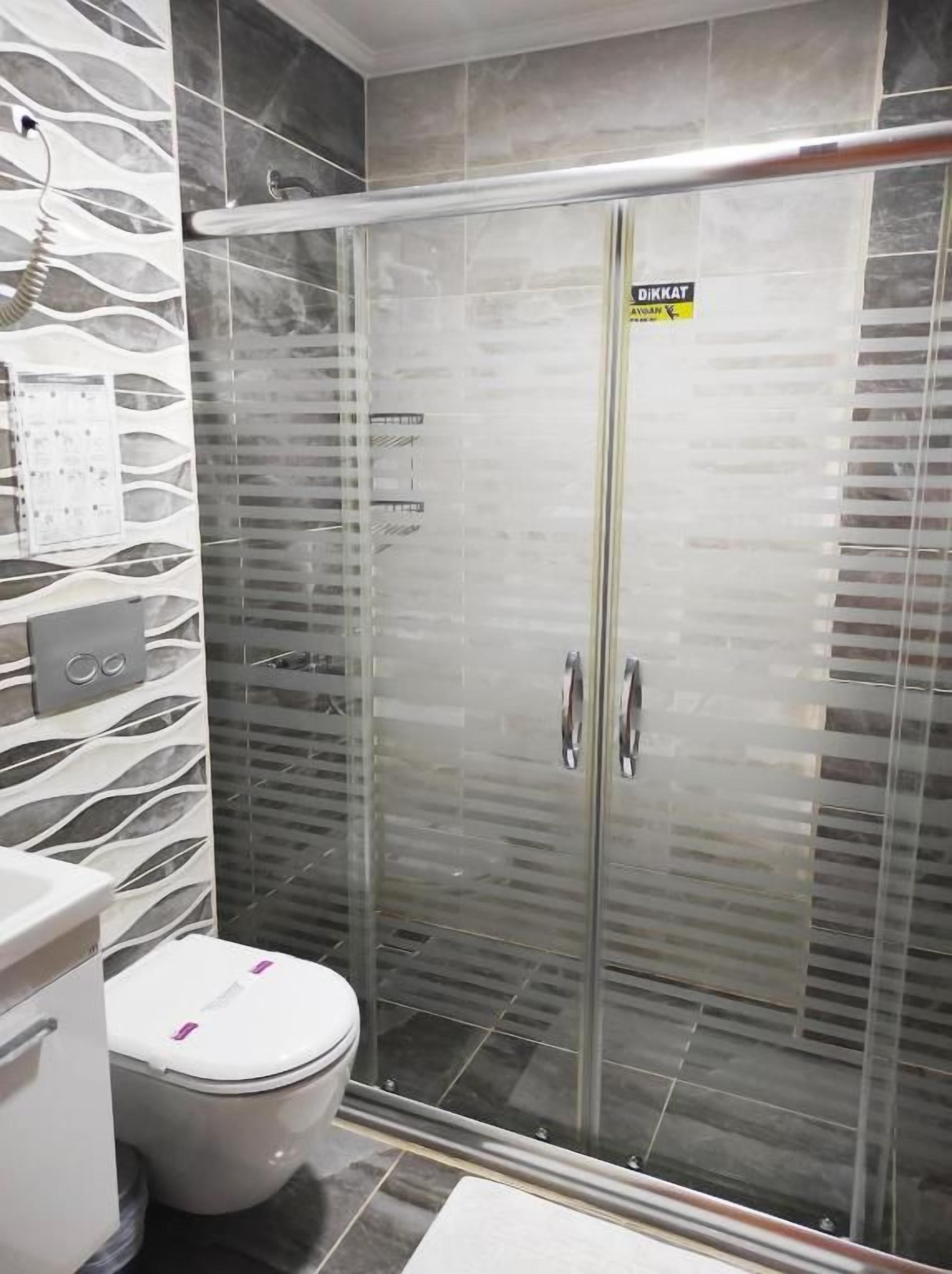 A modern bathroom with a glass-enclosed shower, a white toilet, and a marble-patterned wall.