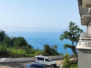 A white car parked on a paved area with a view of the sea. - Amasra Sunrise Otel (Amasra)