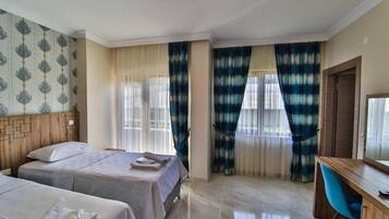 A hotel room with two beds, a desk, and a chair.
