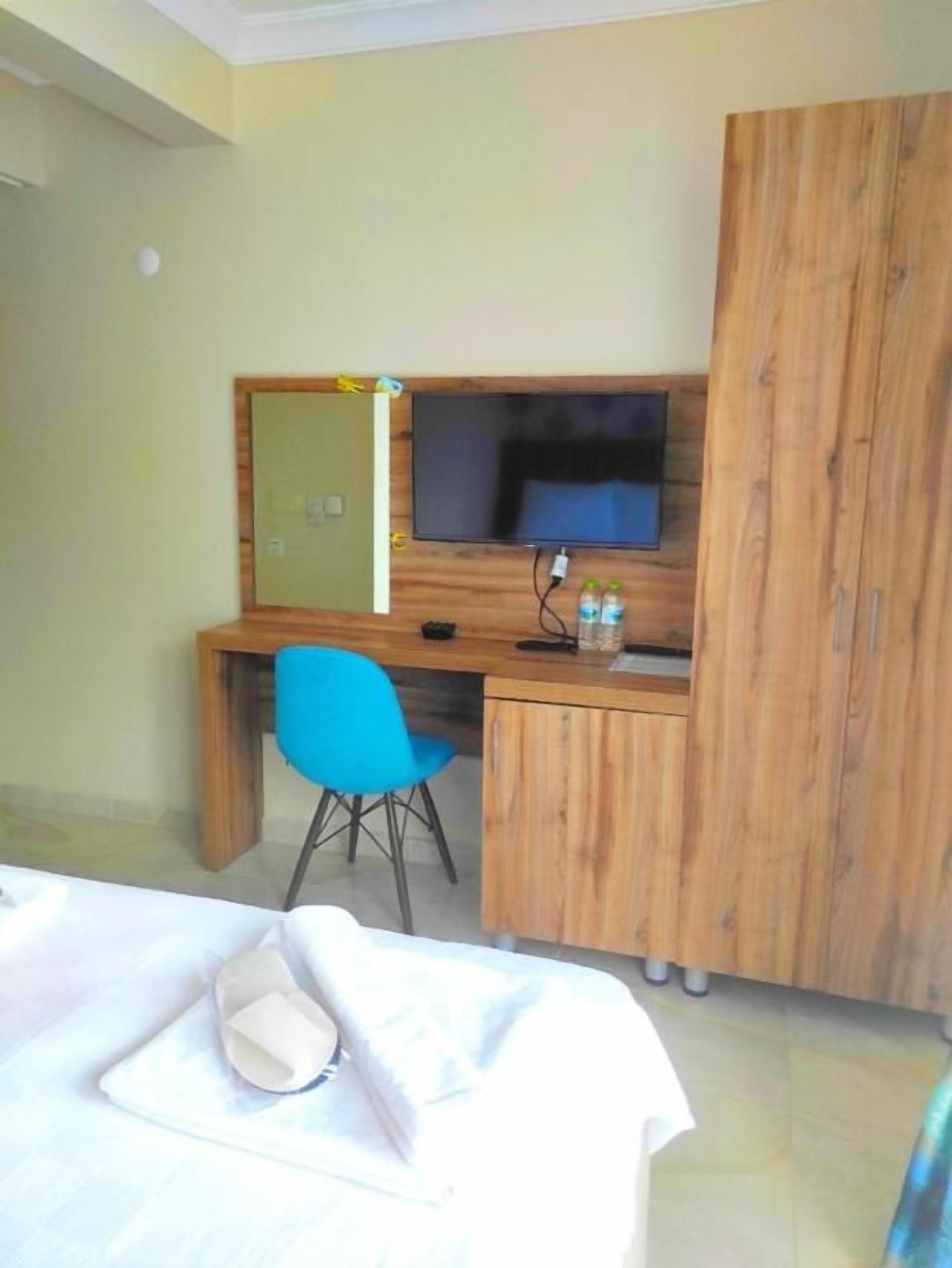 Ein Hotelzimmer mit einem Bett, einem Schreibtisch mit Stuhl, einem Fernseher und einem Kleiderschrank.