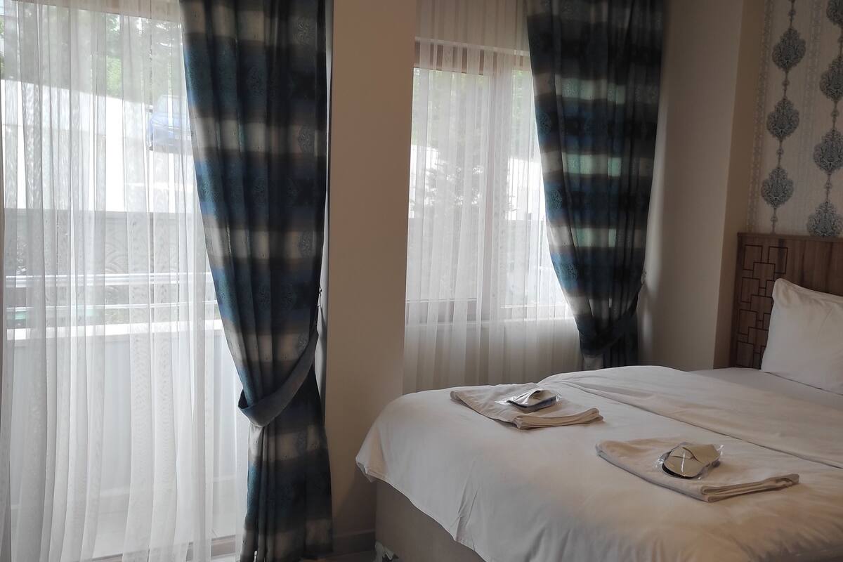 Una habitación de hotel con cama, cortinas y vistas por la ventana.