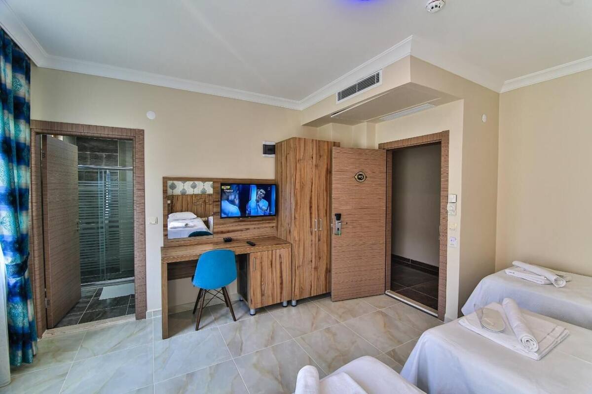 Habitación de hotel con cama, escritorio con computadora y televisor, ducha y armario.