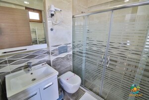 Un baño con lavamanos, inodoro y cabina de ducha con mampara de vidrio.