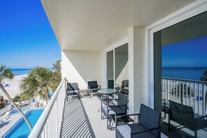 Un balcon avec piscine, vue sur la plage et espace salon extérieur.