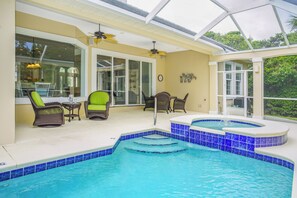 Un área de piscina con jacuzzi, mobiliario exterior y un porche con paredes de vidrio.