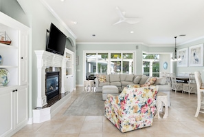 A spacious living room with a fireplace, a sofa, and a dining area with a table and chairs.