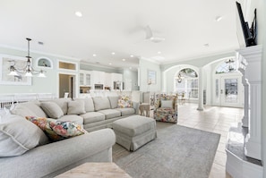 A spacious living room with a sectional sofa, ottoman, and a dining area with a table and chairs.