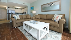 A living room with a beige sofa, a white coffee table, and a patterned rug. - Calypso Resort by BBG (Panama City Beach)