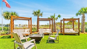 A patio area with wooden pergolas, cushioned seating, and a fire pit. - Calypso Resort by BBG (Panama City Beach)