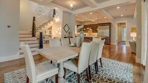 A spacious dining area with a large table and chairs, a staircase leading to a loft, and a modern kitchen in the background. - Dream Weaver - 1232968 (Santa Rosa Beach)