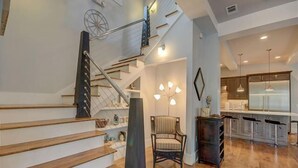 A modern kitchen with bar stools, a wooden staircase, and a chandelier. - Dream Weaver - 1232968 (Santa Rosa Beach)