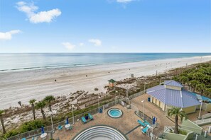 Een resort met een zwembad, ligbedden en uitzicht op het strand.