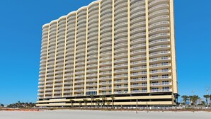 Un hotel de gran altura con varios balcones, techo plano y ubicación frente a la playa.