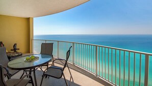 Un balcón con mesa y sillas, con vista a un mar azul y despejado.