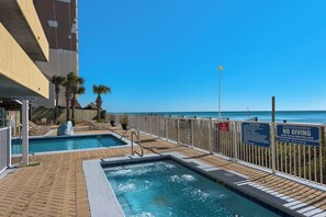 A pool area with a view of the ocean, a sign prohibiting diving, and a sign indicating no glass on hot tubs or pool decks.