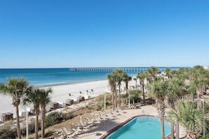 A beach resort with a swimming pool, lounge chairs, and a pier in the background. - Calypso Resort by BBG (Panama City Beach)