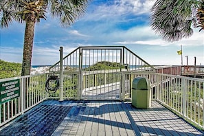 A wooden deck with a metal gate leading to a beach.