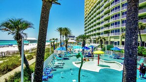 A resort pool area with lounge chairs, umbrellas, and a view of the beach and ocean. - Boardwalk Resort 1806 - 556193 (Panama City Beach)