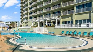A hotel pool area with a clear blue pool, lounge chairs, and a multi-story building with balconies. - Boardwalk Resort 1806 - 556193 (Panama City Beach)