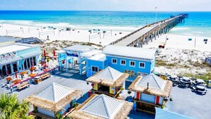 Un hôtel situé en bord de mer, doté de bâtiments à toits de chaume, d’une jetée s’avançant dans l’océan et d’une plage de sable.