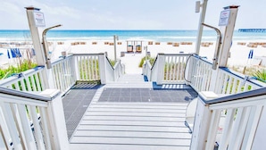 Un escalier en bois mène à une zone de plage d’où l’on a une vue sur l’océan.