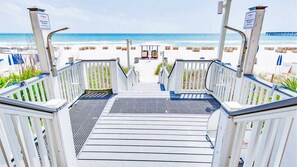 Un escalier en bois mène à une zone de plage d’où l’on a une vue sur l’océan.