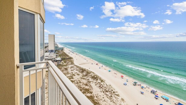 A beach view from a balcony with a clear sky, ocean, and beachgoers. - Emerald Beach 1525 (Panama City Beach)