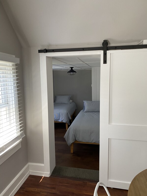 Un dormitorio con dos camas, ventilador de techo y puerta corrediza.