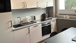 Una cocina moderna con armarios blancos, estufa negra y una ventana con persianas.