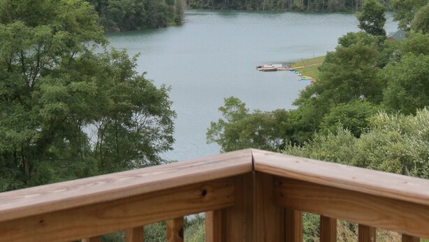 A lake surrounded by dense forest, with a wooden deck in the foreground.