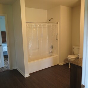 A bathroom with a bathtub, toilet, and shower curtain.