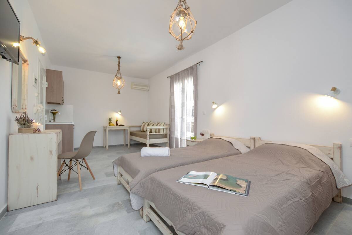A bedroom with two beds, a desk, a chair, and a wardrobe.