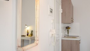 A bathroom with a mirror, a vanity with a candle, and a small table with a vase of flowers. - Casa Verde di Naxos (Naxos)