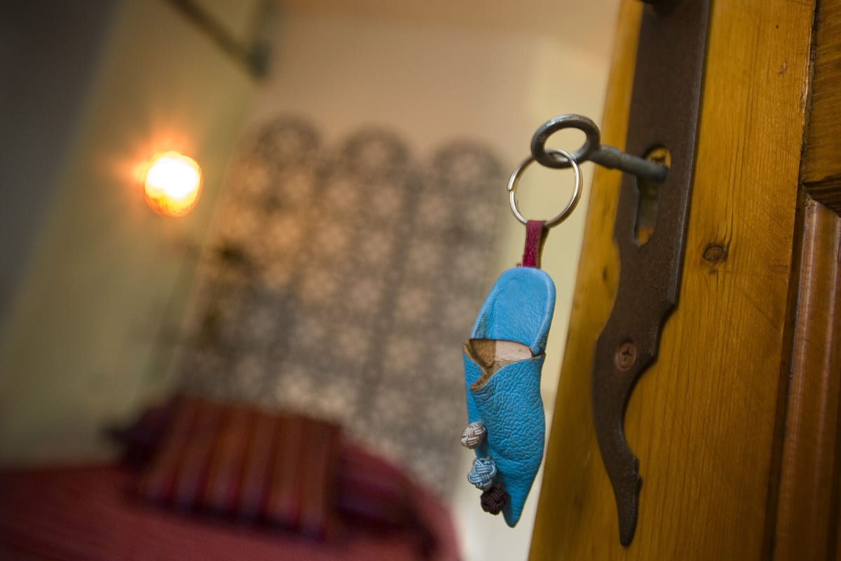 A keychain hanging on a door handle in a room with a bed and a wall-mounted light fixture.
