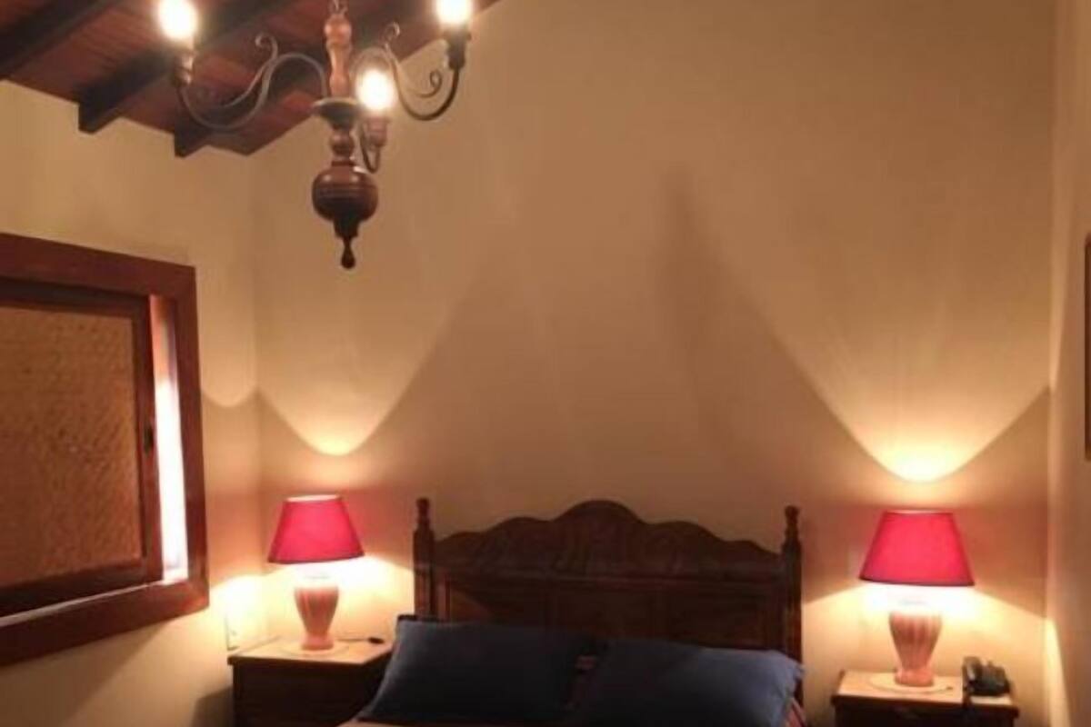 A bedroom with a wooden bed, two bedside lamps, and a chandelier.